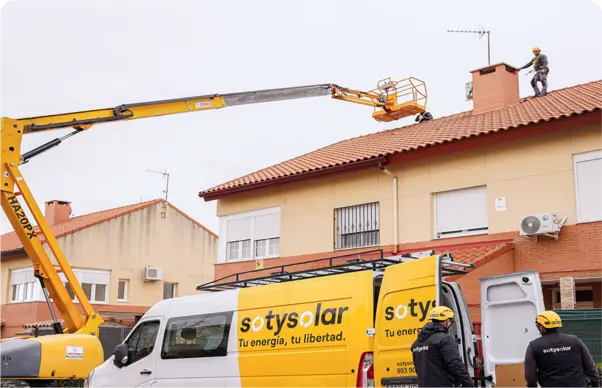 Grua que participa en una instalación de placas solares junto a la furgoneta del equipo de la empresa SotySolar
